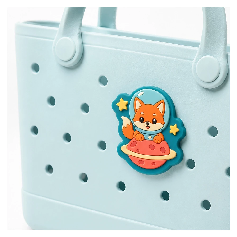 Close-up of a die-cut soft PVC astronaut fox bag charm on a blue tote UK