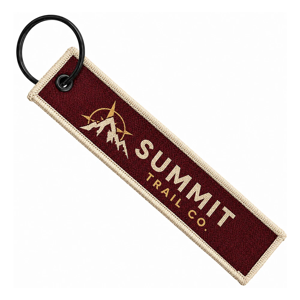 Custom woven keychain — burgundy Summit Trail Co. flight tag with cream border UK