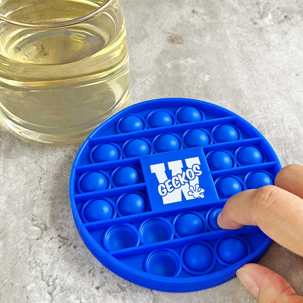 Finger pressing a bubble on a custom blue silicone pop coaster