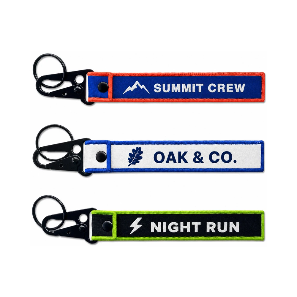 Custom woven keychains with black snap hook — Summit Crew, Oak & Co., and Night Run flight tags